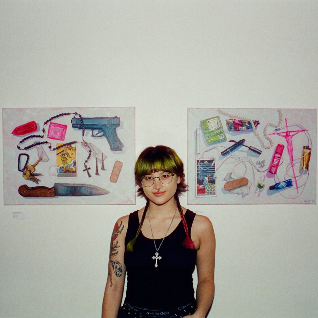 nat belacse welch poses in front of two of their oil painted still lives (whats in yr bag and what protects you)